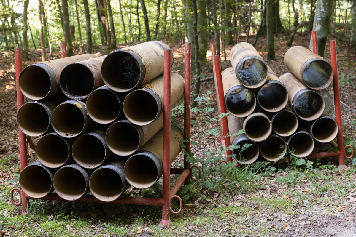 Aufeinander gestapelte Bohrrohre im Wald.